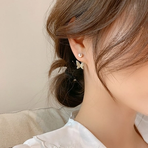 Detailed close-up of gold butterfly pearl earrings worn on a model for elegant look
