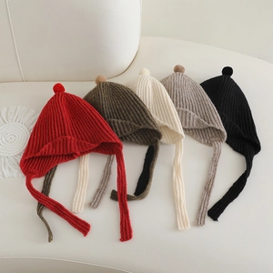 Cinq bonnets en maille pour enfants avec pompons et détails de texture côtelée étalés