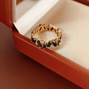 Detail of a gold-plated ring with black rectangular zircon and small white crystals in a box