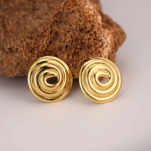 Macro detail of gold spiral earrings with polished finish on a natural rock surface
