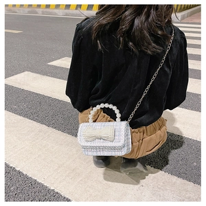 Detail of blue tweed crossbody bag for kids with pearl bow decoration and golden chain
