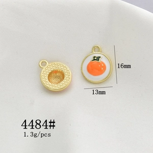 Detail view of 16x13mm gold alloy persimmon charm with orange enamel finish and texture