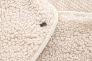 Detailed macro view of off-white sherpa fabric texture with buttonhole and stitched edge