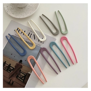 Nine matte U-shaped hair pins in various candy colors on a magazine background