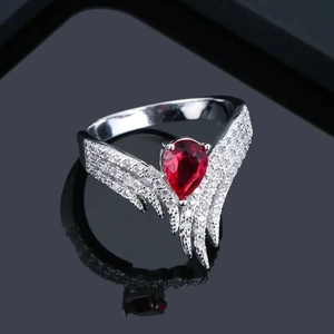 Détail d'une bague avec zircon rouge en forme de goutte et design d'ailes étincelantes