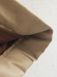 Macro detail of the beige canvas fabric texture and durable double-stitch sewing seams
