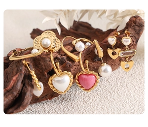 Close-up of vintage gold heart earrings with pearls and resin on a rustic wood stand