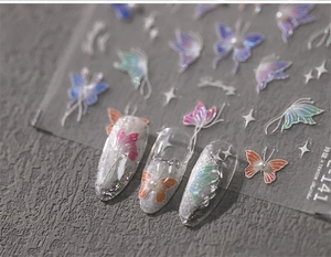 Detailed view of 5D butterfly nail decals with aurora colors and pearl embellishments