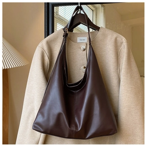 Close-up of a high-quality dark brown leather tote bag hanging on a minimalist clothes rack