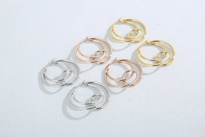 Detailed view of interconnected knot earrings in gold, silver and rose gold finishes