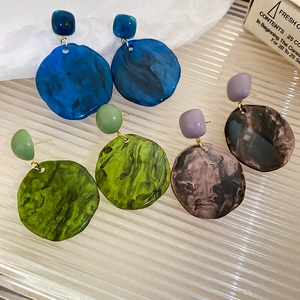 Macro detail of large resin hoop earrings with marble texture in blue, green and brown