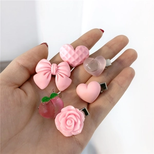 Detailed view of six pink resin hair clips featuring hearts, peaches, and floral designs
