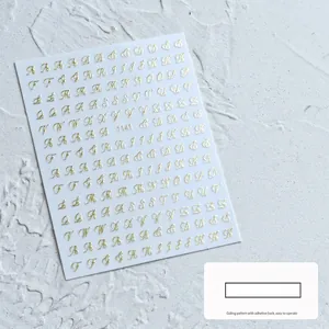 Gedetailleerde macro-opname van 3D gouden cursieve letter nagelstickers voor manicure decoratie