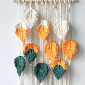 Handwoven macrame wall hanging with feather leaves in beige, orange, and dark green