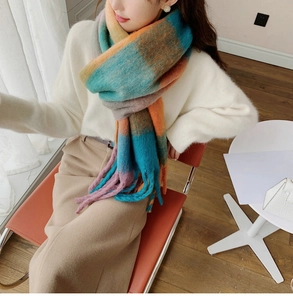 Close-up of thick rainbow plaid scarf with long fringes on a model in a warm setting
