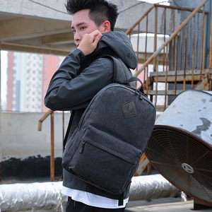 Deep grey canvas backpack with diamond patch shown from a side view on a model