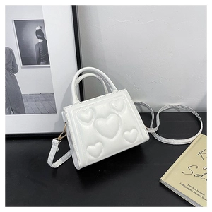 Détail d'un sac à main blanc en cuir verni avec texture de cœur gaufrée et bandoulière