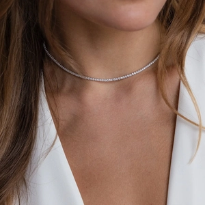 Detailed view of a silver tennis necklace with single-row zircon micro-paving on a model