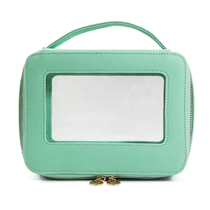 Mint green cosmetic travel case with transparent window and dual gold zippers on white background