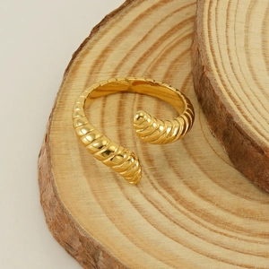Golden ribbed caterpillar open ring in stainless steel displayed on natural wood layers