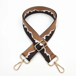 Detail of adjustable brown nylon bag strap with white zigzag pattern and gold metal hardware