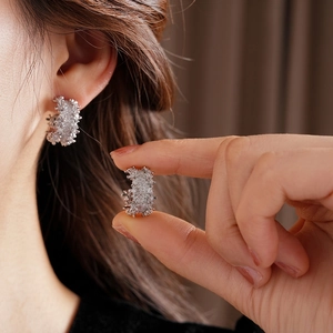 Elegant silver C-shaped stud earrings featuring micro-pave cubic zirconia on models ear