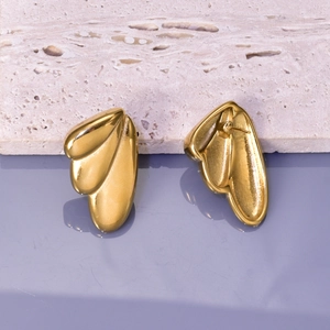 Nahaufnahme goldener abstrakter Blatt-Ohrstecker aus Edelstahl auf Stein-Hintergrund