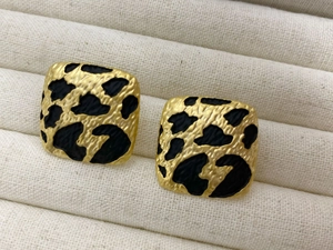 Close-up of square leopard print earrings in black and gold on a jewelry tray