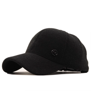 Close-up of black corduroy baseball cap with metal M logo and thick winter texture