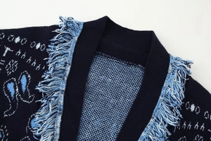Detail of navy knit cardigan featuring light blue patterns and thick fringe trimmings