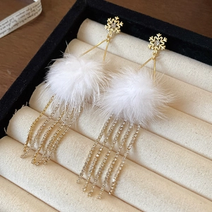 Detail of snowflake earrings with fluffy white fur balls and sparkling rhinestone tassels