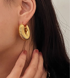 Close-up of textured chunky gold hoop earrings with vintage croissant design on a model