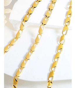 Close-up of a 18k gold plated geometric chain jewelry set on white marble background