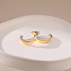 Minimalist C-shaped stud earrings in gold and silver contrast finish with metallic texture