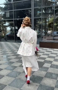Détail d'un blazer à imprimé fleuri pour femme avec ceinture et jupe mi-longue assortie