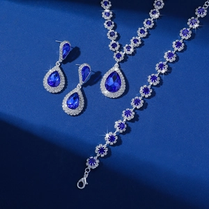 Macro shot of silver jewelry set with blue teardrop crystals on dark blue background