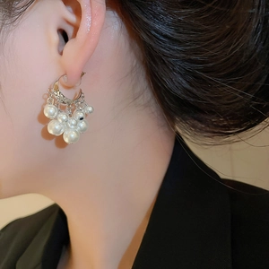 Close-up of elegant C-shaped silver earrings with cascading pearls on model
