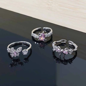 Macro detail of three-piece silver rings featuring pink zircons and butterfly motifs