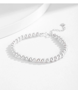 Classic white pearl bracelet with adjustable silver heart charm on a white surface