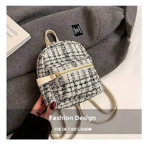 Close-up of black and white tweed plaid mini backpack with beige leather straps and gold zipper