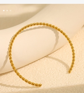 Macro detail of golden twisted rope cuff bracelet with minimalist open C-shape design