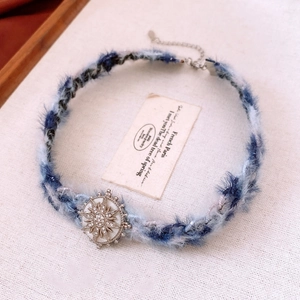 Détail d'un choker en peluche bleu et blanc avec pendentif étoile argenté et strass
