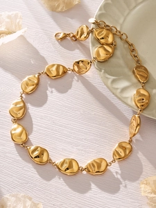 Detailed macro of gold chain necklace with irregular oval metal links on ceramic tray