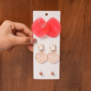 Detailed set of resin geometric earrings in pink and beige on a wooden background