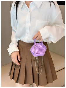 Detail shot of a purple hexagonal chain bag with woven texture held by a model