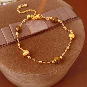 Close-up of gold-plated bracelet with brown tiger eye stones on velvet box
