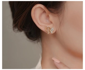 Close-up of hollow butterfly stud earring with sparkling zircon inlay and golden finish