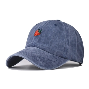 Close-up of a washed navy blue cotton baseball cap with a small strawberry embroidery