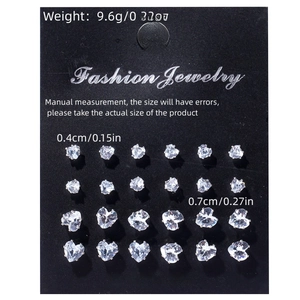 Macro shot of 12 pairs of silver-toned heart and round crystal stud earrings on black card