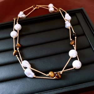 Détails de l'œil de tigre et des perles baroques sur un collier à chaîne torsadée